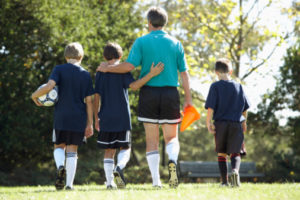 Coach and Boys Soccer Team Leaving Soccer Field